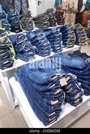 Straight rows of denim trousers of different shades lie on the shelves in a clothing store Stock Photo