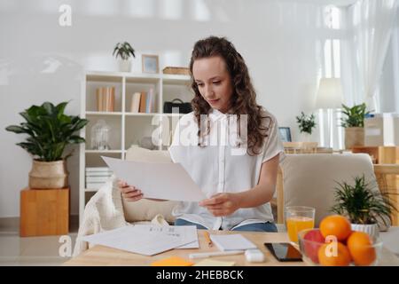 Smiling young manager checking documents with application interface layout made by UI designer Stock Photo
