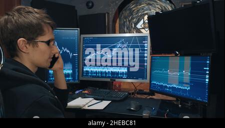 Male trader, a freelancer discusses stock exchange quotation charts on the phone Stock Photo