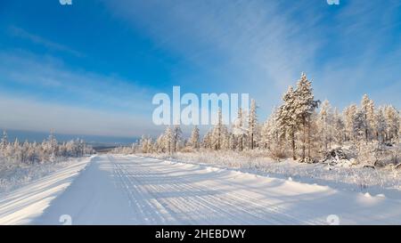 Road in the winter forest on a sunny day. South Yakutia, Russia Stock Photo