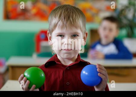 A preschooler boy holds colored balls in his hand. Stock Photo