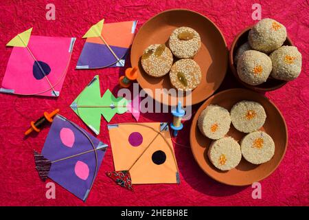 Til Gul or Sweet white sesame seeds Laddu with kites and phirki. Makar sankranti festival food background. Til baati with laddo Stock Photo