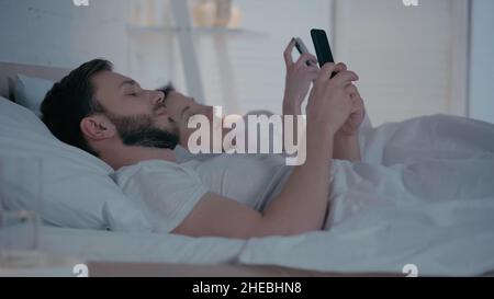 Young couple using smartphones on bed at home Stock Photo
