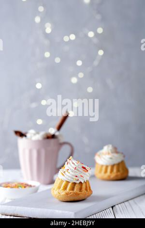Vanilla muffins with cream cheese cream and caramel sprinkles on a wooden background. Copy space. Stock Photo