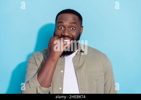 Photo of young african man bite fists trouble fail scared reaction isolated over blue color background Stock Photo