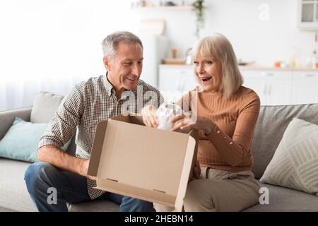 Senior Customers Couple Unpacking Cardboard Box With New Vase Indoor Stock Photo