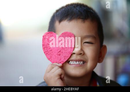 Asian boy with red heart shape in hand and very happy for design in your work valentine concept. Stock Photo