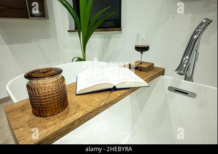 Wooden shelf on a freestanding bathtub - soak in the tub and relax with a red wine and a book Stock Photo