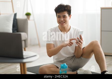 Asian guy doing exercises watching online tutorial Stock Photo