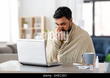 sick indian man having video call on laptop Stock Photo