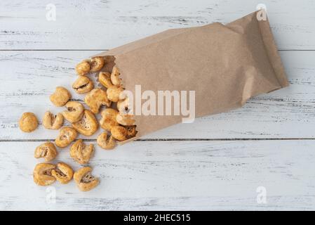 Canjica, hominy or white corn popcorn, sweet popcorn in a bag over wooden table. Stock Photo