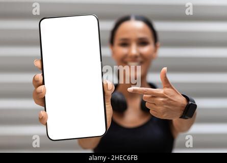 Fitness App. Sporty Young Woman Pointing At Big Blank Smartphone In Hand Stock Photo