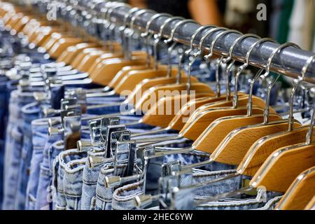 Various blue Jeans on a hanging rack in the clothes store. Close-up, selective focus Stock Photo