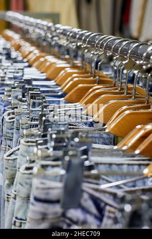 Various blue Jeans on a hanging rack in the clothes store. Close-up, selective focus Stock Photo