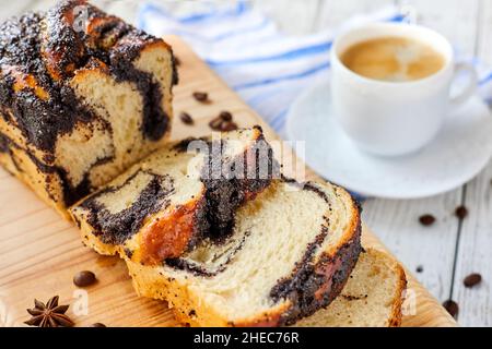 Homemade poppy roll with a cup of coffee on wooden background. Close-up, selective focus Stock Photo