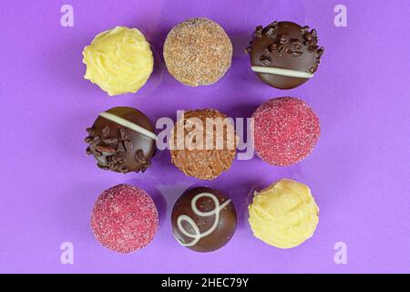 Chocolate pralines top view stock images. Chocolate candies on a lilac background. Chocolate frame top view. Square-shaped chocolate pralines Stock Photo