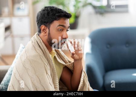 sick indian man using nasal spray at home Stock Photo