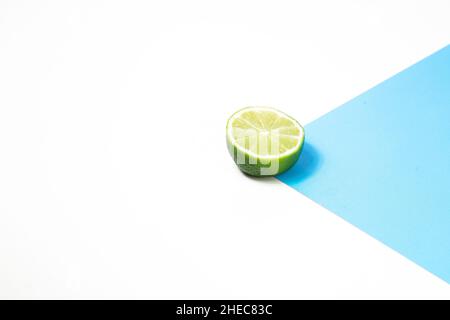 Sliced lemon or lime on abstract geometric white and blue background. Citrus abstract background. Stock Photo