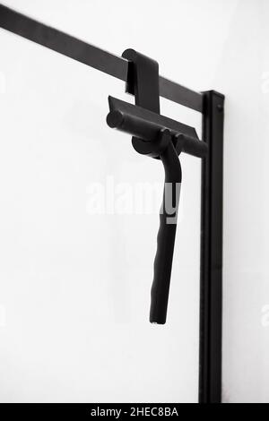 window glass squeegee. Window cleaning black brush is appendant on shower glass. Stock Photo