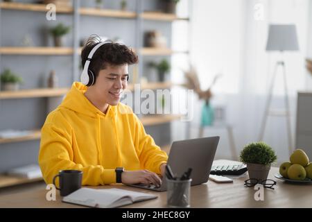 Smiling asian man in headset using laptop at home Stock Photo