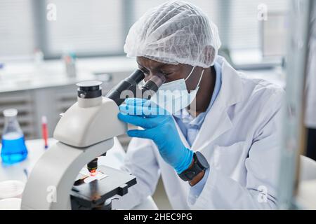 Biochemical research scientist working with microscope for coronavirus vaccine development in pharmaceutical research labolatory Stock Photo