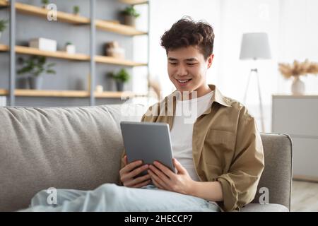 Smiling asian man using digital tablet at home Stock Photo