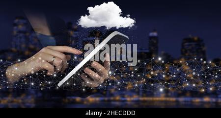 Abstract cloud technology digital. Communication network. Hand touch white tablet with digital hologram cloud sign on city dark blurred background Stock Photo