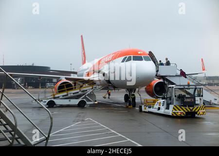 Passengers board / boarding Airbus A320-214 plane aircraft number G-EZWP operated by Easyjet on apron at Gatwick airport, London. UK. (Christmas / 128) Stock Photo