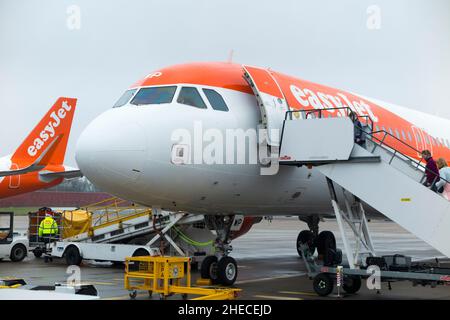 Passengers board / boarding Airbus A320-214 plane aircraft number G-EZWP operated by Easyjet on apron at Gatwick airport, London. UK. (Christmas day / 128) Stock Photo