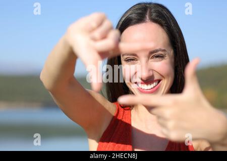 Front view portrait of a happy woman smiling framing with hands at camera Stock Photo
