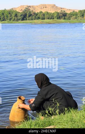 Egypt, Upper Egypt, Nile valley, Egypt, Upper Egypt, Nile valley, Bassaw island (north of Kom Ombo), village woman filling a jar with water from the Nile Stock Photo