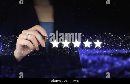 Customer Experience Concept.Hand holding digital graphic pen and drawing digital hologram five stars sign on city dark blurred background. Increase ra Stock Photo