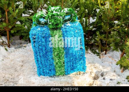 Large stylized New Year's gift on the background of Christmas trees outdoors Stock Photo