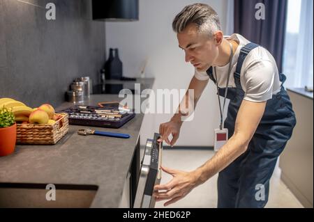 Man looking at information on control panel of dishwasher Stock Photo