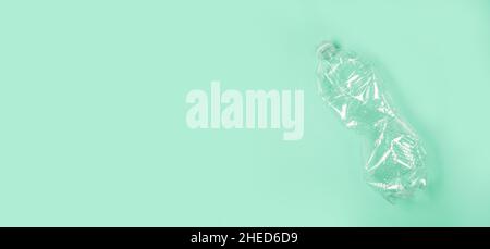 Used rumpled plastic bottle on green background. Ecology problem. Top view, copy space. Plastic trash. Stock Photo