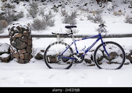 An old mountain bike leans against a wooden rail fence after a winter snow. Stock Photo