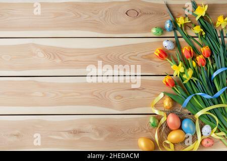 Happy Easter card. Congratulatory easter background. Easter eggs and flowers on wooden background. Stock Photo