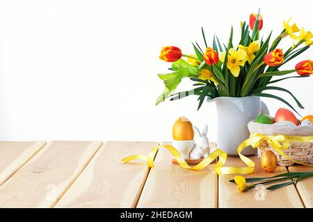 Happy Easter. Congratulatory easter background. Easter eggs and flowers on wooden background. Stock Photo