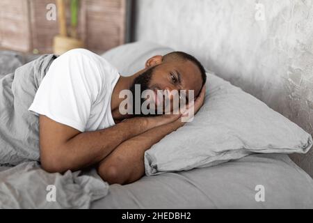 Black man lying in bed and thinking Stock Photo