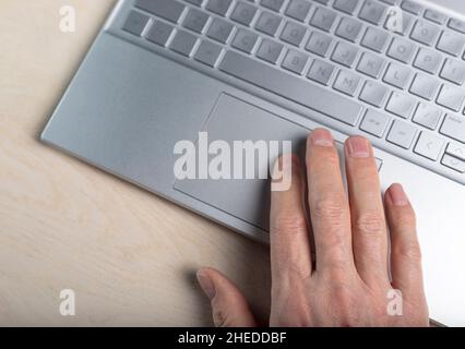 Hand on laptop touchpad, tapping and scrolling with fingers closeup. Stock Photo