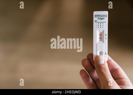 a girl's hand containing the rapid antigen test kit with a positive result during the COVID-19 smear test. Stock Photo
