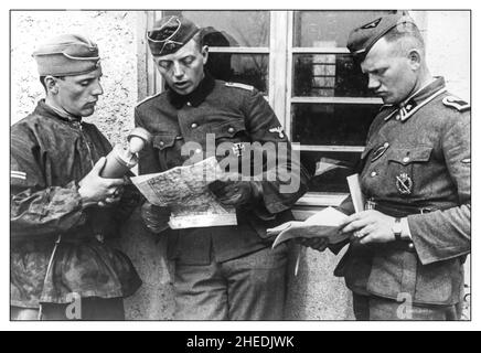 Operation Barbarossa WW2 Propaganda image of Nazi SS-Hauptsturmfuhrer Fritz Klingenberg, officer of the 2nd SS Panzer Division 'Das Reich' (center), who was the first to break into Belgrade at the head of a 9-man squad, gives an interview to a radio reporter. Fritz Paul Heinrich Otto Klingenberg was a German officer in the Waffen-SS who served with the SS Division Das Reich and was a commander of the SS Division Götz von Berlichingen. Stock Photo