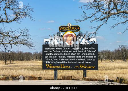 03-2016 Bartlesville OK USA - Welcome sign to Woolaroc Museum and Wildlife Preserve with founder Frank Phillips picture and teepees with barren branch Stock Photo