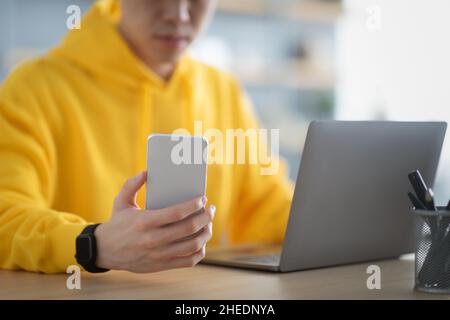 Asian man sitting at desk using cell phone Stock Photo