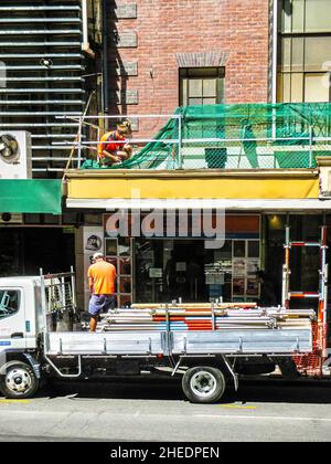 09-2014 Brisbane Australia - Worken  doing repairs  on building in city - one on balcony and one on truck below filled with pipes Stock Photo