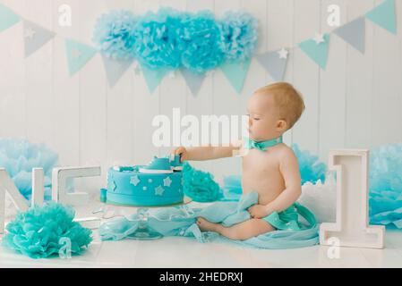 Birthday party for a one-year-old boy in blue and turquoise garlands and a cake, holiday concept and decor, a child with a cake Stock Photo