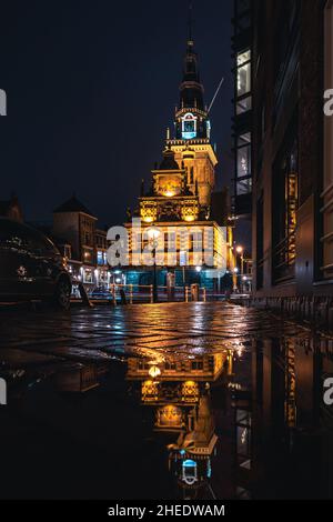 The Waag building reflected in a puddle. The stripes are from passing cars, the Netherlands Stock Photo