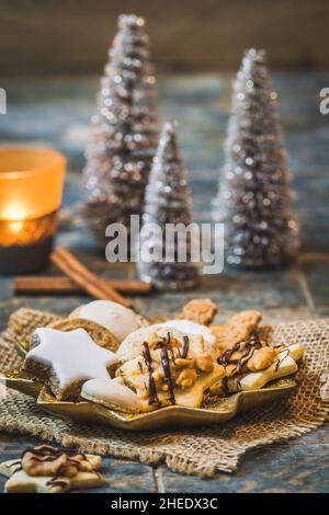 Christmas cookies on a star shaped plate with christmas decoration and candle light, vertical Stock Photo
