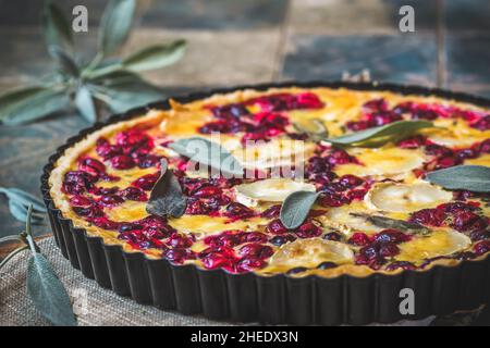 Cranberry goat cheese tart with sage on rustic blue background Stock Photo