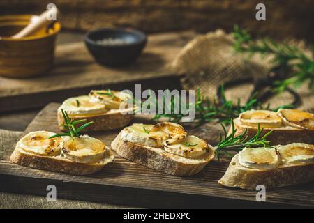 Baguette bread slices baked with goat cheese and honey, decorated with rosemary Stock Photo